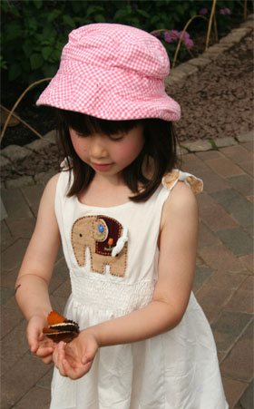A butterfly lands in the hands of a young girl.